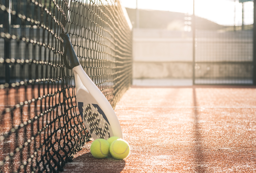 padel racket en ballen op speelveld